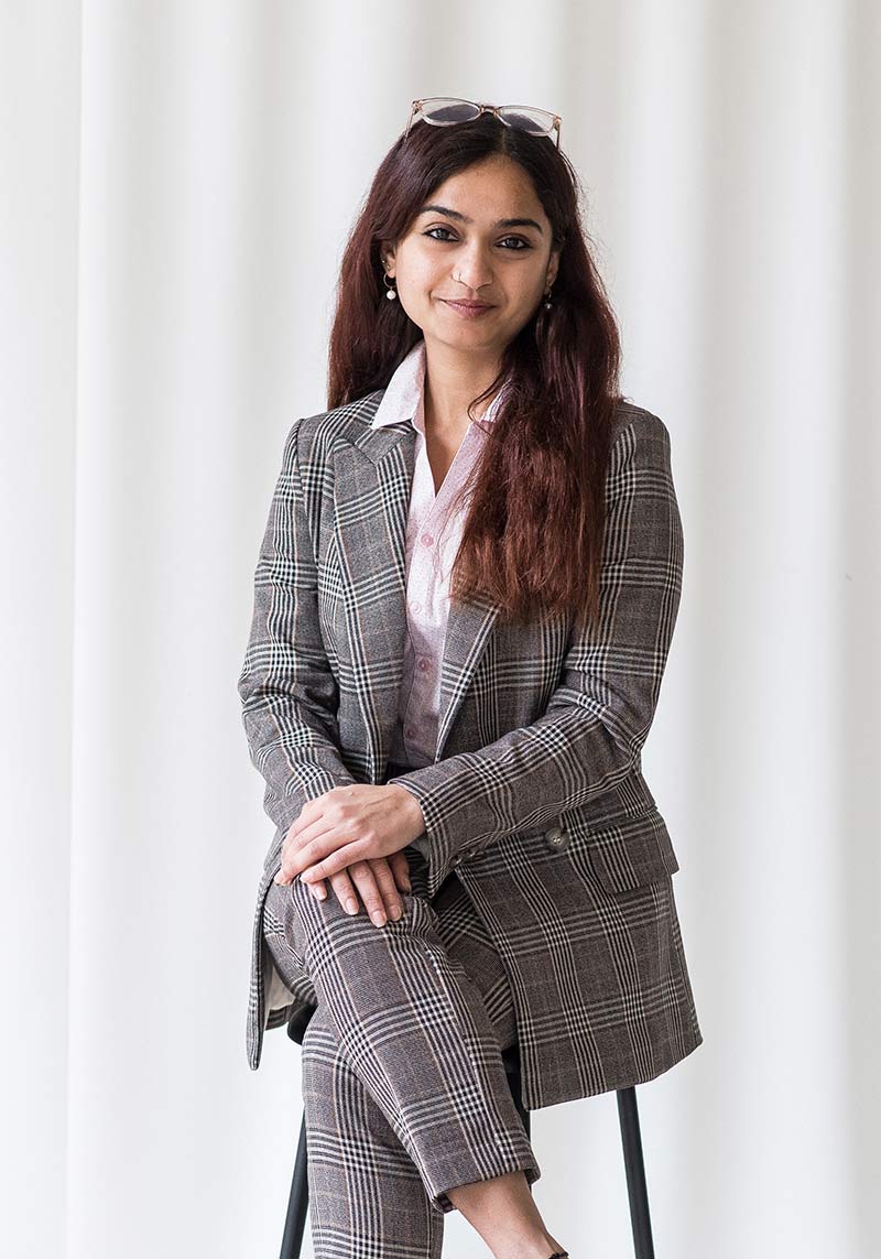 minerva bc smiling women in business attire sitting on stool with glasses on top of head