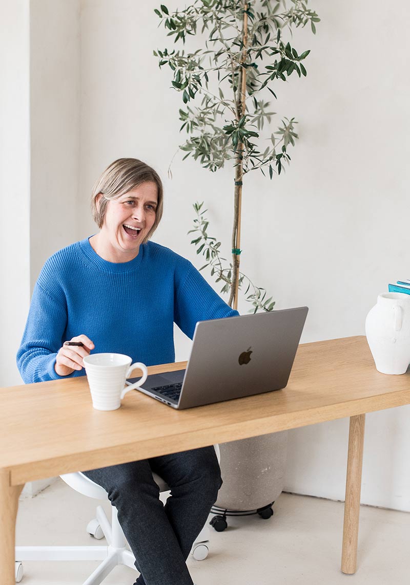 minerva bc women working at table with laptop plant in background